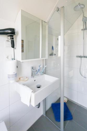 a white bathroom with a sink and a shower at Steife Brise in Büsum
