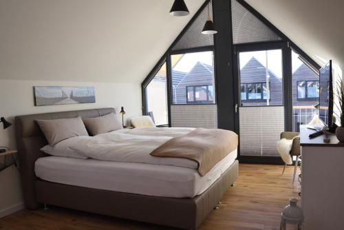 a bedroom with a large bed and large windows at Sandbank in Büsum