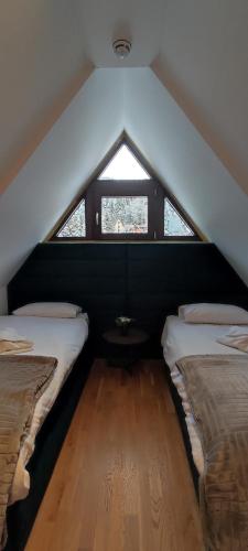 a attic room with two beds and a window at Vila Irina Kopaonik in Kopaonik