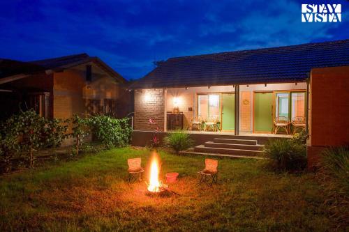a fire in the yard of a house at night at StayVista at Sunnyside Homestay with Bonfire & Lawn in Honnekere