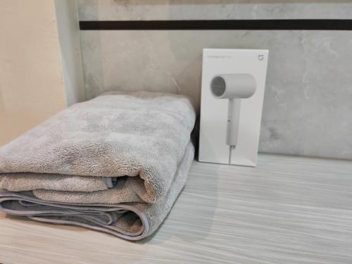 una pila de toallas sentadas junto a una caja blanca en UG Homestay BP - Netflix & 4 Air-Con Rooms, en Batu Pahat