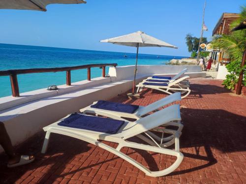 2 Liegestühle und ein Sonnenschirm auf dem Balkon mit Meerblick in der Unterkunft Blue Tides Hotel in Nungwi