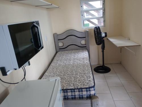 a small room with a chair and a television at quarto com banheiro privativo in Florianópolis