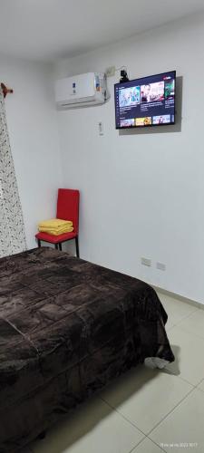 a bedroom with a bed and a chair and a tv at Dptos Lencinas in Las Heras