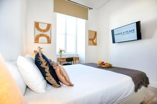 una camera con letto bianco e TV a parete di Hot Breeze Apartment a Faro