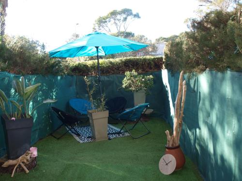 a patio with two chairs and a blue umbrella at Studio le Mistral in Saint-Raphaël