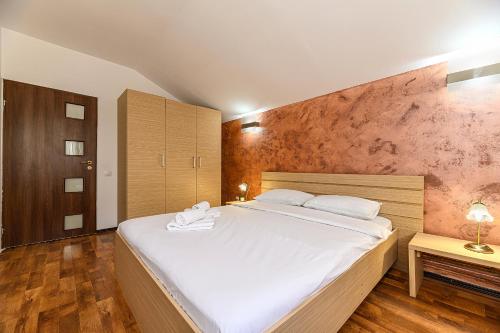 a bedroom with a large white bed and wooden floors at Elite Neagoe Apartment in Braşov