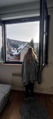 a girl is looking out of a window at Vila Irina Kopaonik in Kopaonik