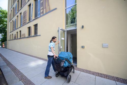 a woman pushing a stroller on a sidewalk next to a building at Book Hotel Leipzig in Leipzig