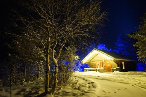 una cabaña de madera en la nieve por la noche en Muotkan Ruoktu Tunturikyla en Inari