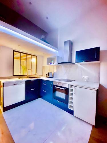 - une cuisine avec des placards bleus et blancs et un évier dans l'établissement Le somptueux Le Gallia, à Cannes