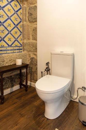 a white toilet in a bathroom with a table at Casa da Judiaria Velha AP in Viseu