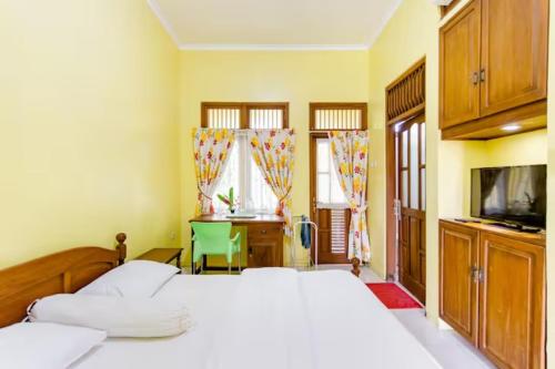 a bedroom with a bed and a desk and a television at Villa Alicia in Yogyakarta