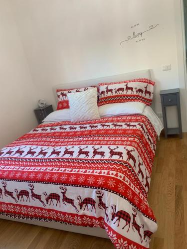 a bed with a red blanket with horses on it at Appartamento sul mare Nettuno in Nettuno
