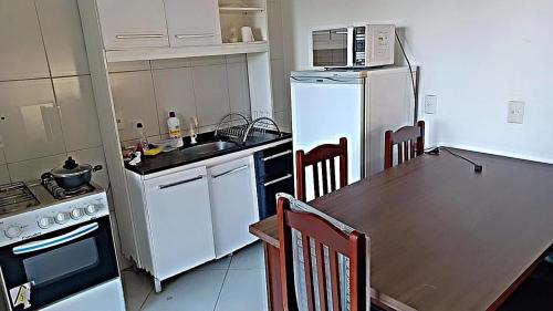 eine Küche mit einem Tisch und einem weißen Kühlschrank in der Unterkunft Kitnet ao lado da Ucs in Caxias do Sul