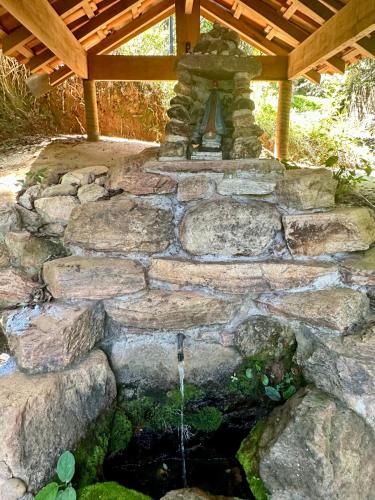 a stone retaining wall with a water fountain at Chalé Recanto Luz Da Montanha in Águas de Lindóia