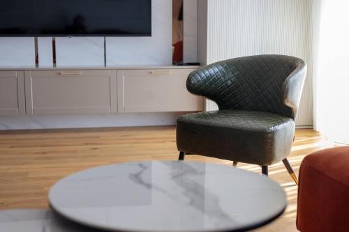 a living room with a chair and a table at DONNER LUXURY APARTMAN in Subotica