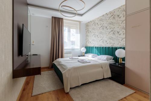 a bedroom with a bed and a flat screen tv at DONNER LUXURY APARTMAN in Subotica