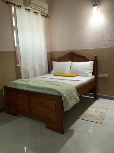 a bed with a wooden frame and white pillows at Zebra House III StoneTown in Ngambo