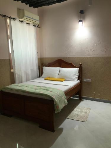 een slaapkamer met een bed met een gele deken erop bij Zebra House III StoneTown in Ngambo
