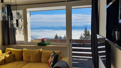 a living room with a couch and a large window at Gerlitzen-Apartments in Kanzelhöhe