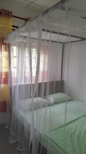 1 dormitorio con cama con dosel y ventana en Happy Haven Villa, en Weligama