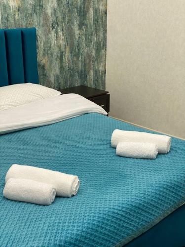 Una cama azul con dos toallas enrolladas. en City hotel, en Karakol