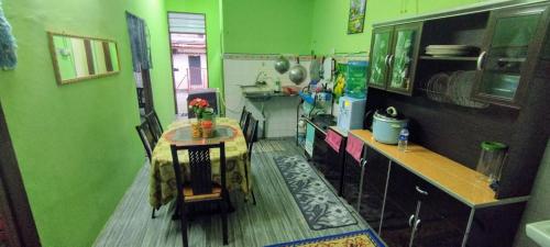 cocina con paredes verdes, mesa y barra en Homestay D'Murni, en Kampung Gurun