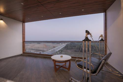 a room with a table and a chair and a large window at Hotel Aditya Mansingh Inn in Somnath
