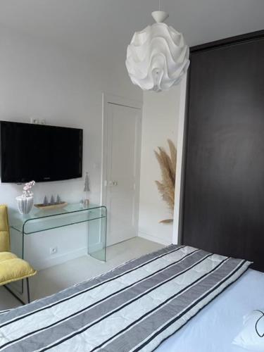 1 dormitorio con 1 cama, TV y lámpara de araña en Chez Céline, en Cherbourg-en-Cotentin