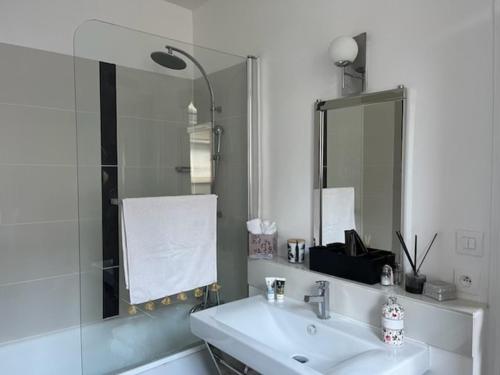 Baño blanco con lavabo y espejo en Chez Céline, en Cherbourg-en-Cotentin