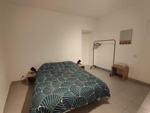 ein Schlafzimmer mit einem Bett mit einer grünen Bettdecke in der Unterkunft T2 aux portes des Cévennes in Lédignan