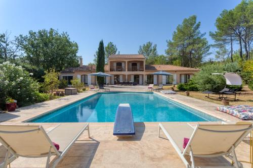 une piscine avec des chaises et une maison dans l'établissement Villa de 277m² climatisée avec piscine chauffée à Fayence, à Fayence