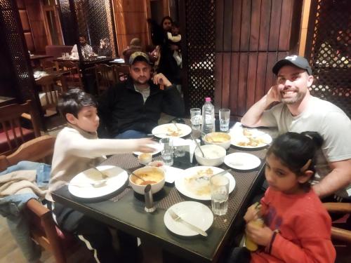 un grupo de personas sentadas en una mesa comiendo comida en H.B Holiday home, en Srinagar