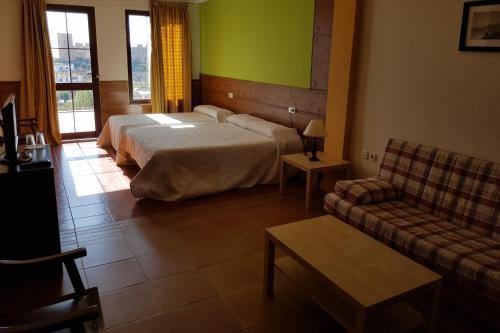 a hotel room with a bed and a couch at Hotel Restaurante Baños in Baños de la Encina