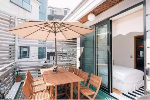 a wooden table and chairs with an umbrella on a balcony at Hanso Presidential Suite Hanok Hotel in Seoul