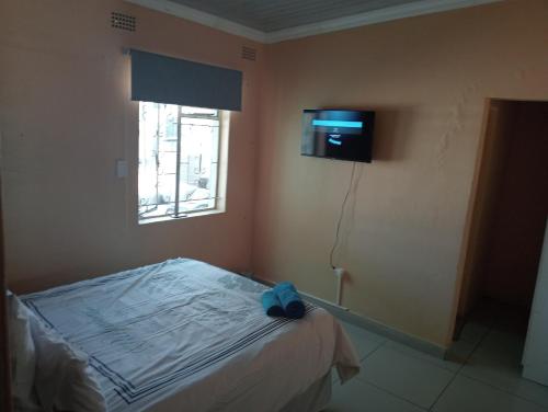 a bedroom with a bed and a tv on the wall at Ngena guesthouse in Cape Town