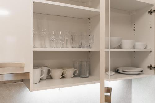 a white cabinet with cups and plates and glasses at Garden Towers in Prague