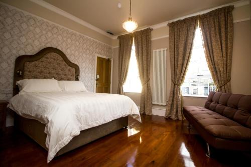 a bedroom with a bed and a couch and windows at The Rose Bed and Breakfast in Stainland