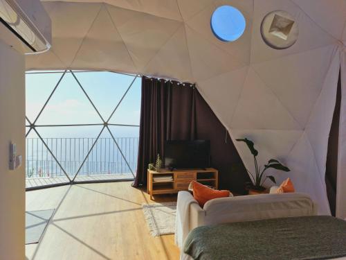 a living room with aamed ceilings and a large window at Vi Naturae Glamping in Fajã da Ovelha