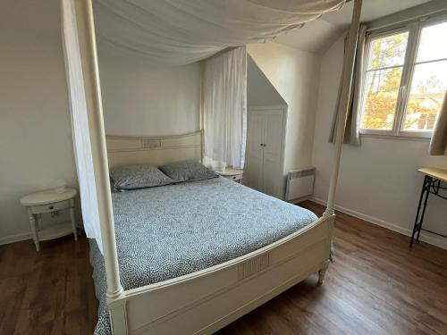sypialnia z łóżkiem z baldachimem w obiekcie Cottage Duplex golf de Limère prox Orléans w mieście Ardon