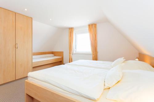 Cette chambre comprend un grand lit blanc et une fenêtre. dans l'établissement Kiefernhaus, à Norderney
