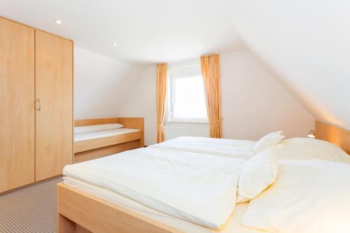 a large white bed in a room with a window at Kiefernhaus in Norderney