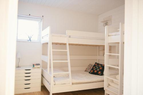 a bedroom with white bunk beds and a desk at Fjällfrid stugby in Bruksvallarna