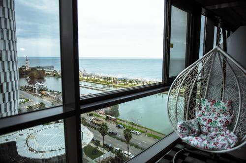 a hanging chair looking out of a window at the ocean at Premium apartments - the star of Batumi Palace in Batumi