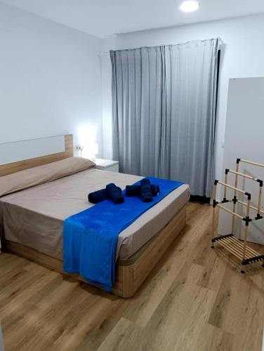 a bedroom with a bed with a blue blanket at Fuerte Vibes Guest House In Corralejo in Corralejo