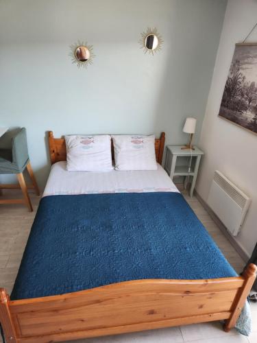 1 dormitorio con cama de madera y manta azul en Charmant studio entre mer et forêt, en Saint-Mandrier-sur-Mer