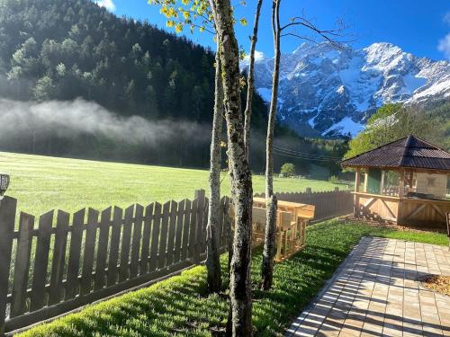 a fence in a yard with mountains in the background at Rooms Kočna in Zgornje Jezersko