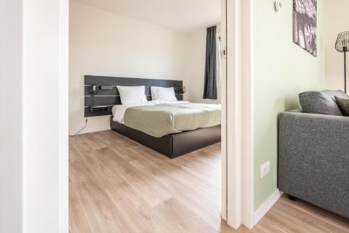 een slaapkamer met een bed en een bank bij Marinaveste Campevaer in Sneek