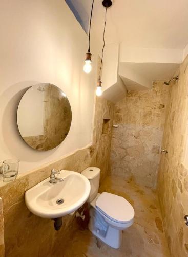 a bathroom with a sink and a toilet and a mirror at Cabaña Villa Jardín - Aldea Doradal - Santorini Colombiano in Doradal